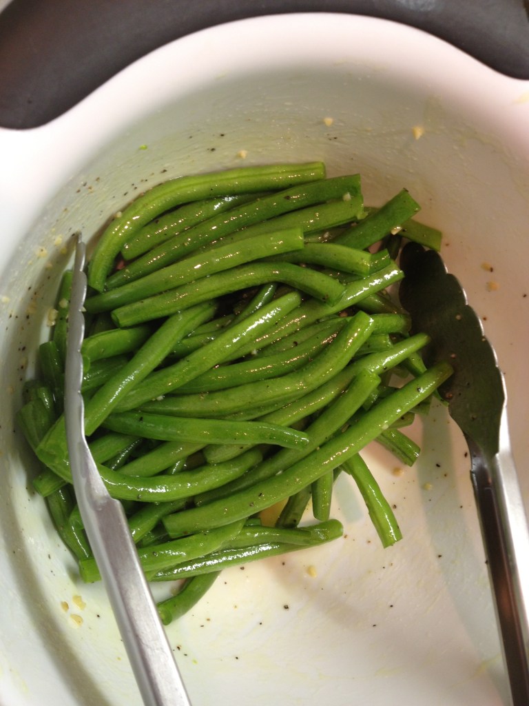 Coating green beans in olive oil and garlic
